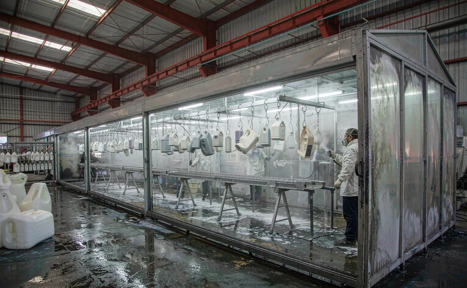 塑料件表面处理间：工人在喷房里对挂具上的塑料面板做喷涂作业