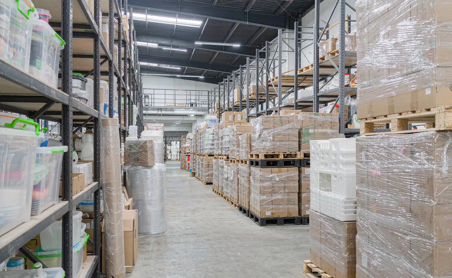 家居塑料件成品仓：货架上分层码放收纳箱与塑料制品，托盘缠膜待发