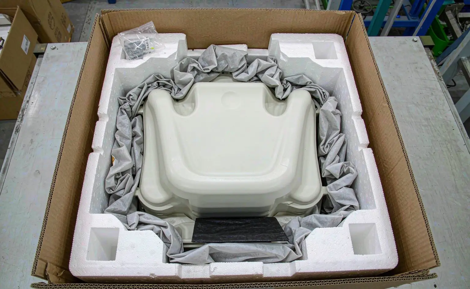 Packing bench: an open appliance carton showing white foam and EPE pearl-cotton liners around the product, with a small moisture-control sachet inside