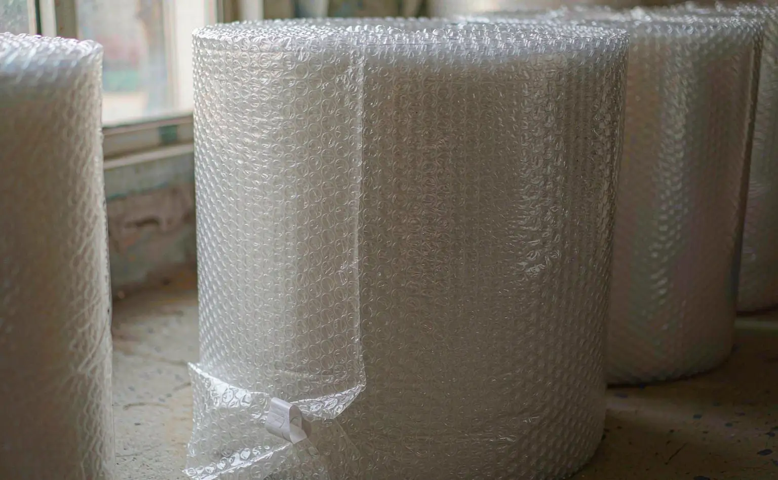 气泡膜卷材：一卷透明气泡膜立在成品区，气泡面朝外，卷口用胶带固定