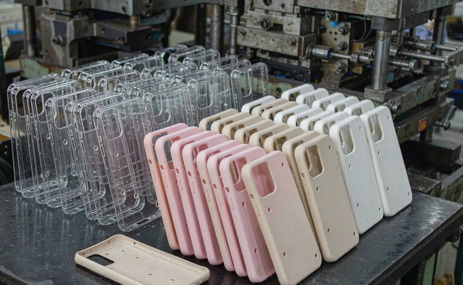 Phone case moulding workshop: freshly demoulded TPU soft cases beside clear PC hard cases