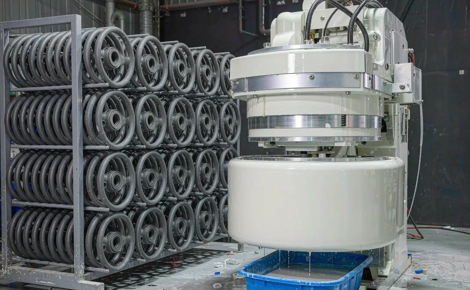 Steering wheel foaming shop: dark grey foamed wheel cores stacked on a rack beside the foaming mould