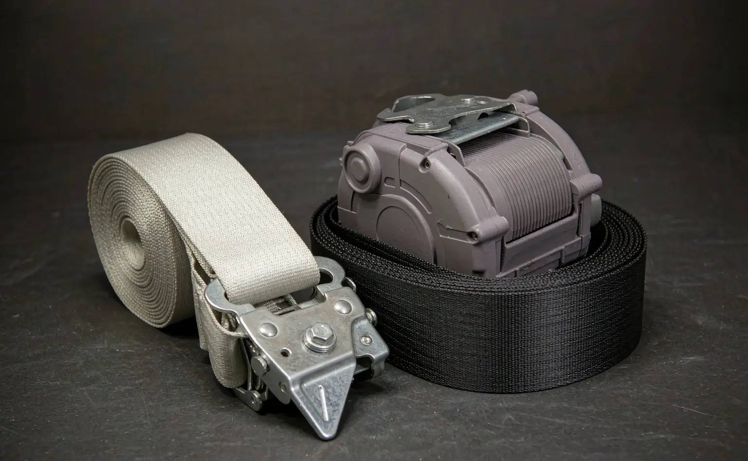 Finished seat belt: coiled high-strength polyester webbing with metal buckle ends on a workbench
