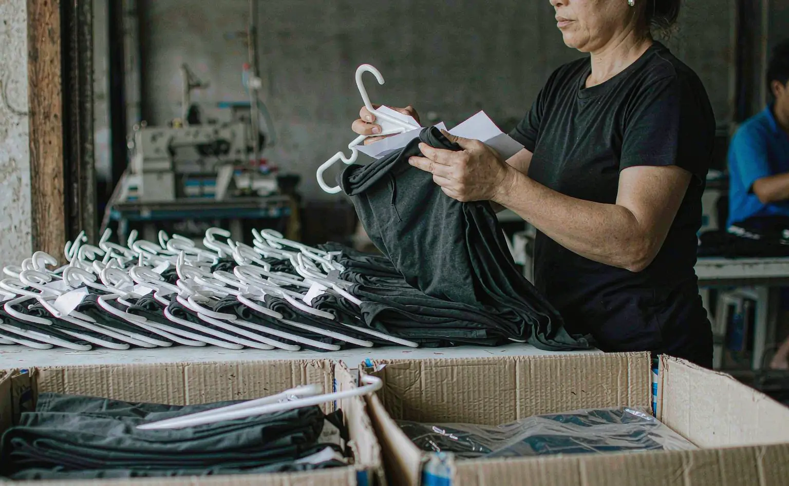 服装出口装箱现场：成衣挂在衣架上叠好放进纸箱，衣架与布料之间垫着一层薄纸