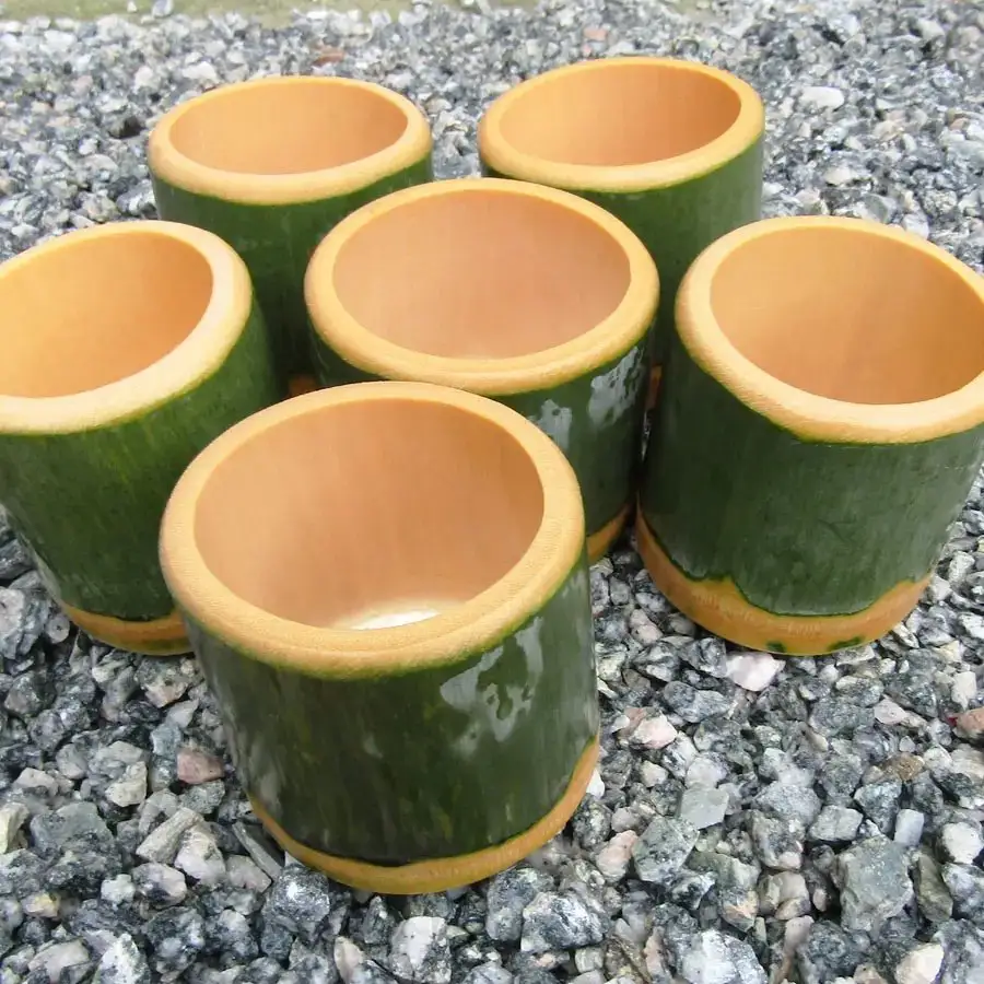 成品区：六只绿皮竹筒杯成排立放在碎石地上，杯口朝上晾着，内壁干净无水痕