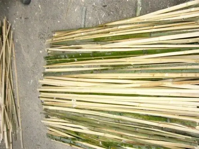 备料区：拆好的竹篾成捆平铺在地面上，篾片一侧保留青皮，另一端是剖开的浅色纤维面